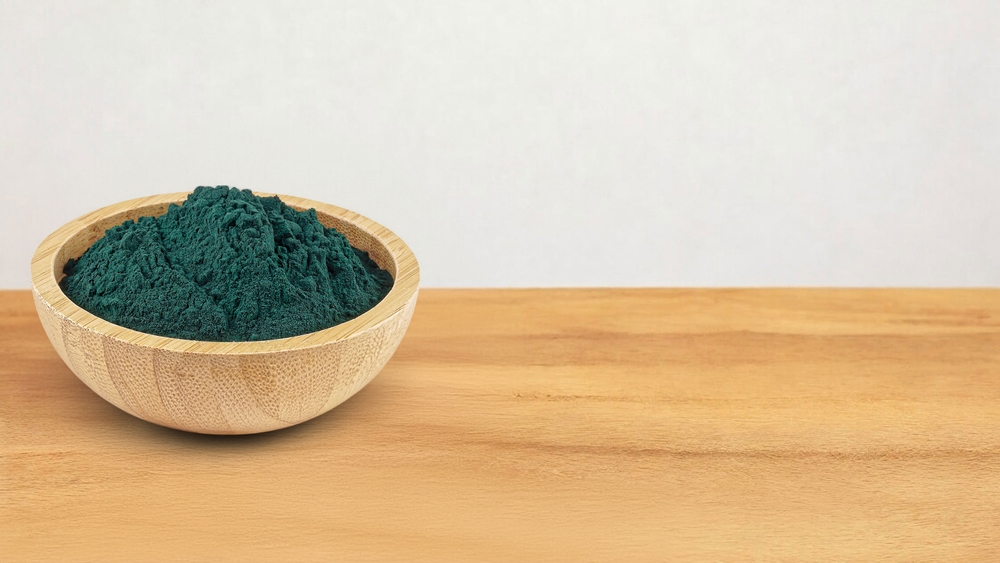 A wooden bowl filled with spirulina powder
