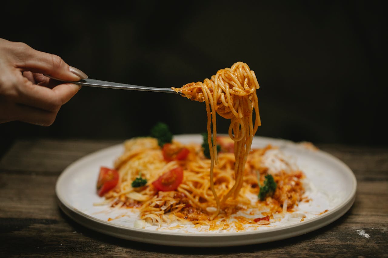 Woman eating Bolognese pasta with fork