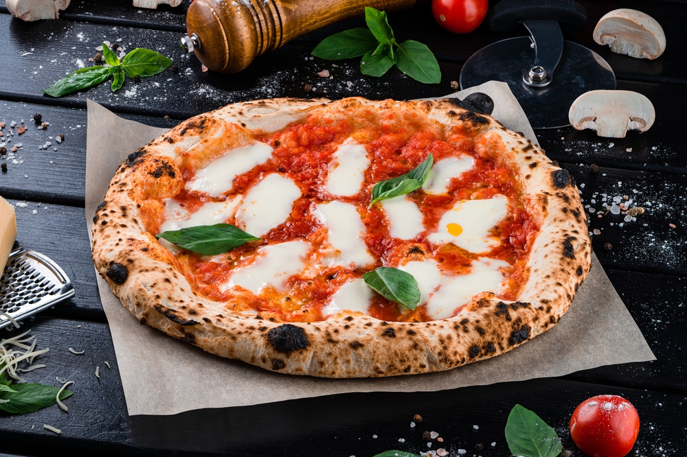Neapolitan pizza with spices, tomatoes and cheese mozzarella on dark background.