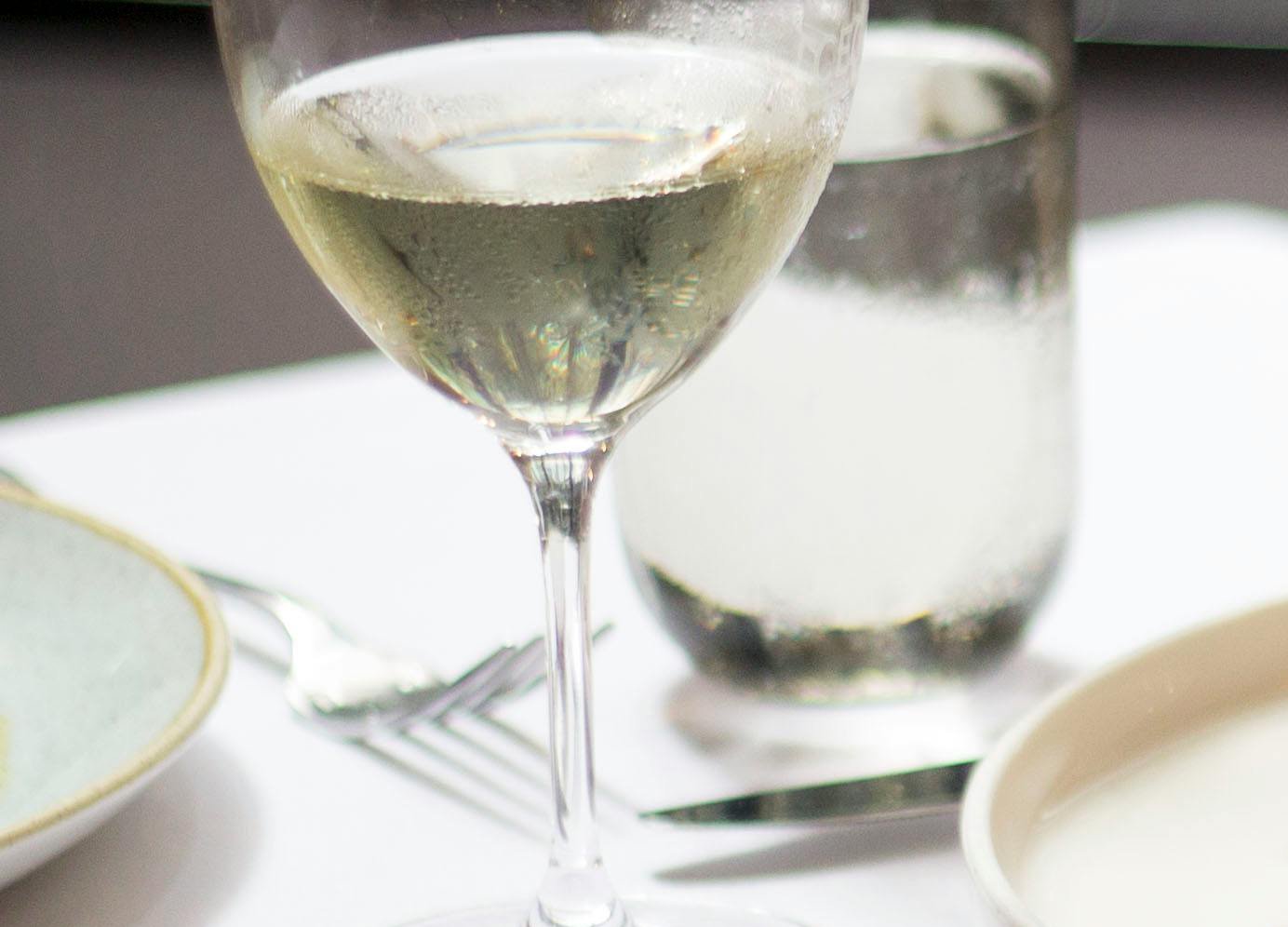 Plate with roasted bird near glasses with drinks near cutlery