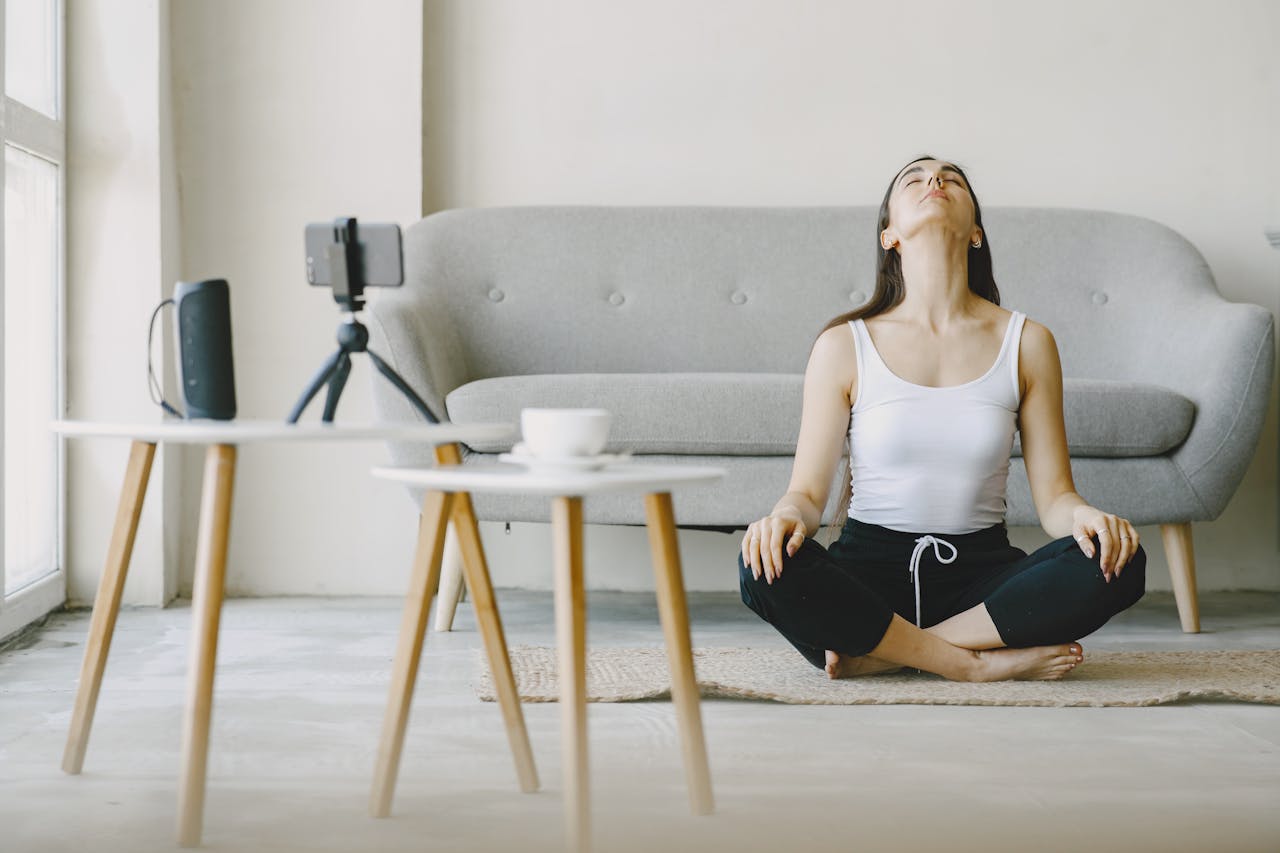 Photo of Woman in a white tank top and black pants Sitting on Rug Meditating