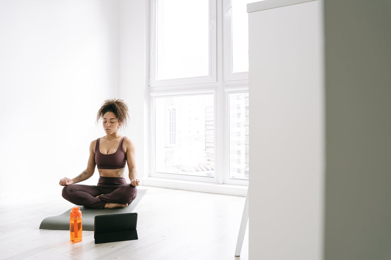 Photo of Woman in a brown tank top and brown pants Sitting on Rug Meditating