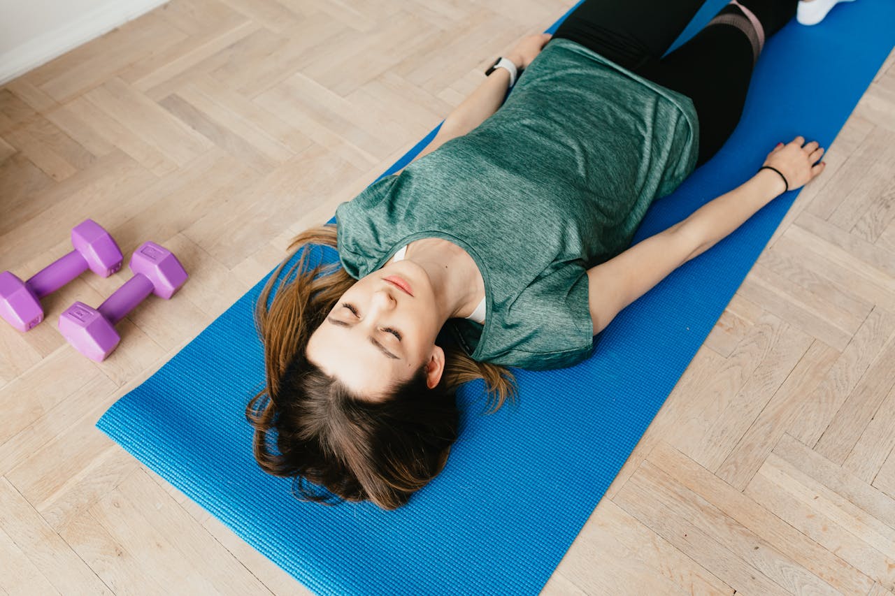 Slim woman lying in Shavasana pose on yoga mat