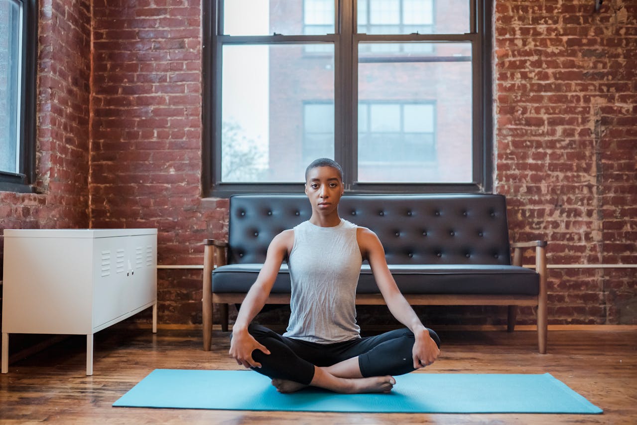 Photo of Woman in a gray t-shirt top and black pants Sitting on Rug Meditating