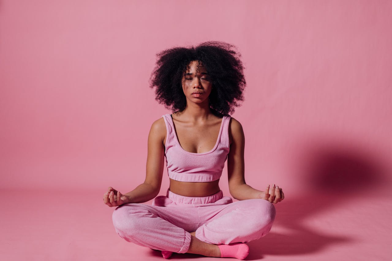 Woman in Pink Crop Top and Jogging Pants Sitting on Floor Meditating