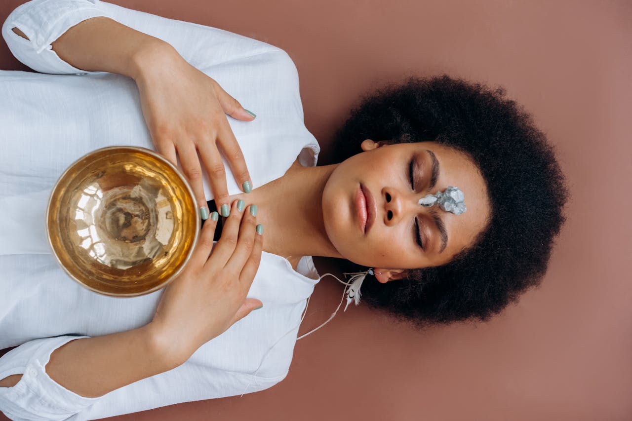 Photo of Woman in a white shirt Lying on the floor with a Tibetan Singing Bowl on her Chest