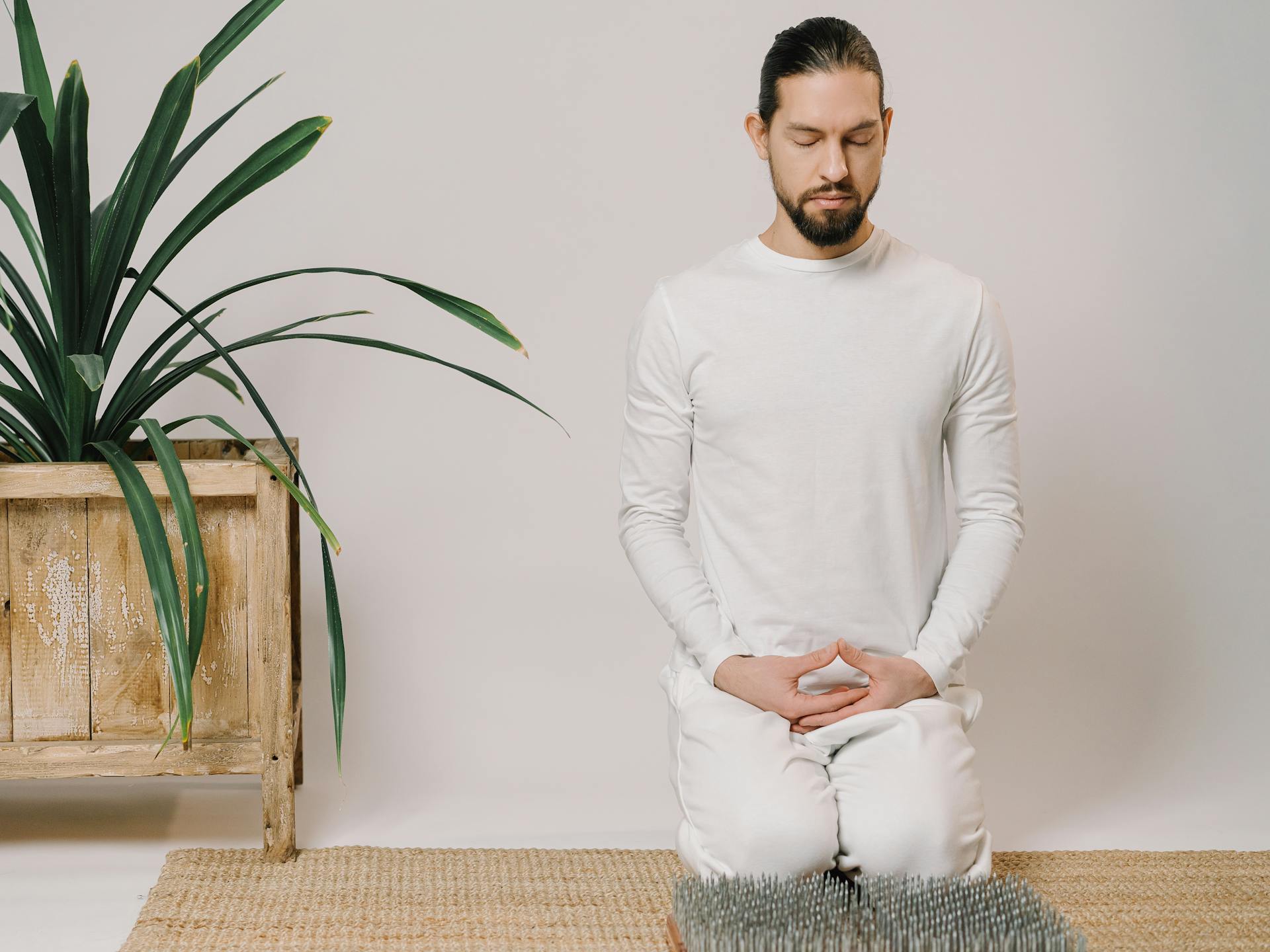 Photo of Man in White T-shirt and White Jeans on Sitting on Floor Meditating