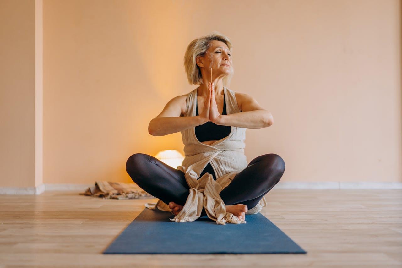 Photo of Mature woman in a black tank top and black pants Sitting on Rug Meditating