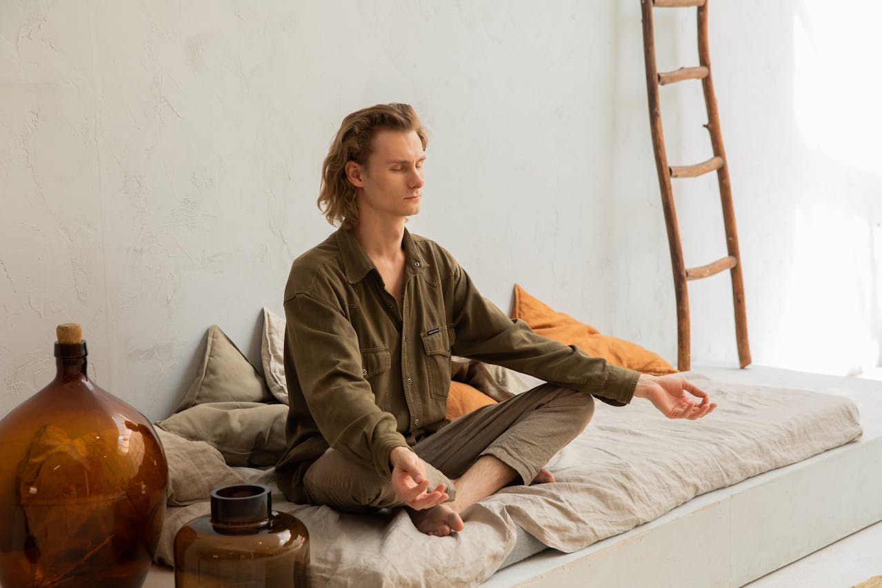 Photo of Concentrated man meditating in Lotus pose on mattress