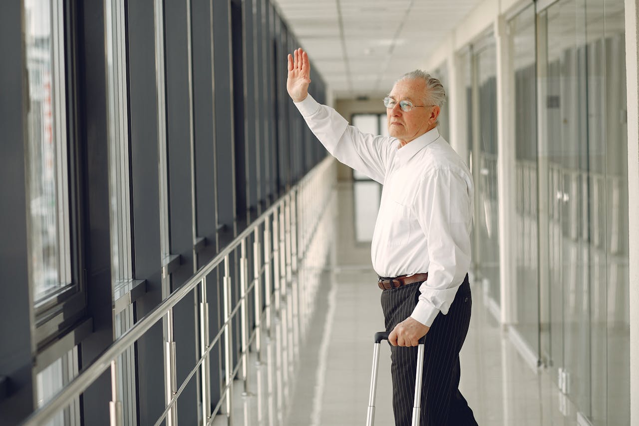 Senior man waving goodbye and walking in airport corridor