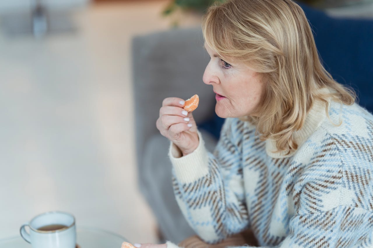 Elderly woman eating fresh mandarin