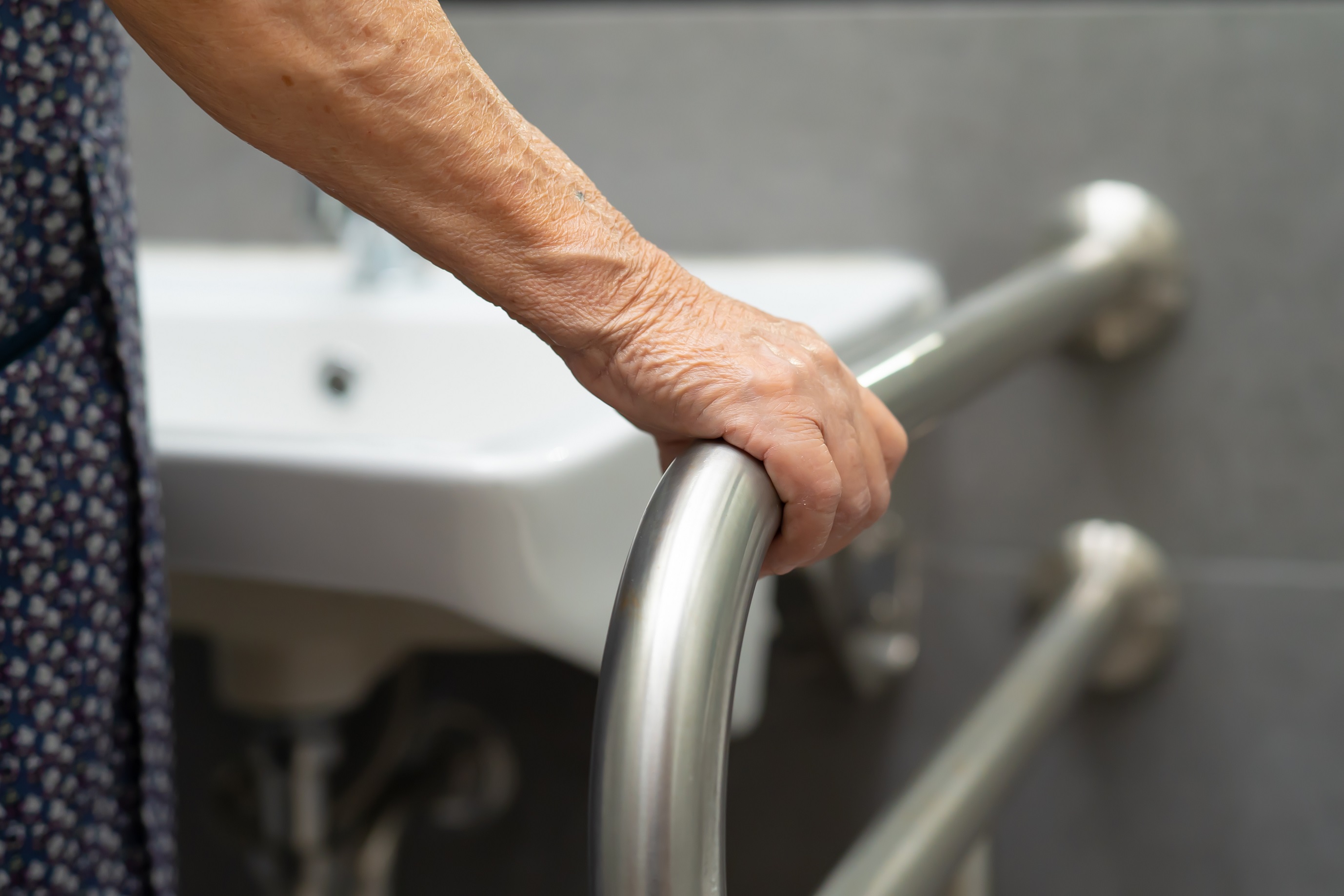 Senior or elderly old woman use toilet bathroom handle for security.