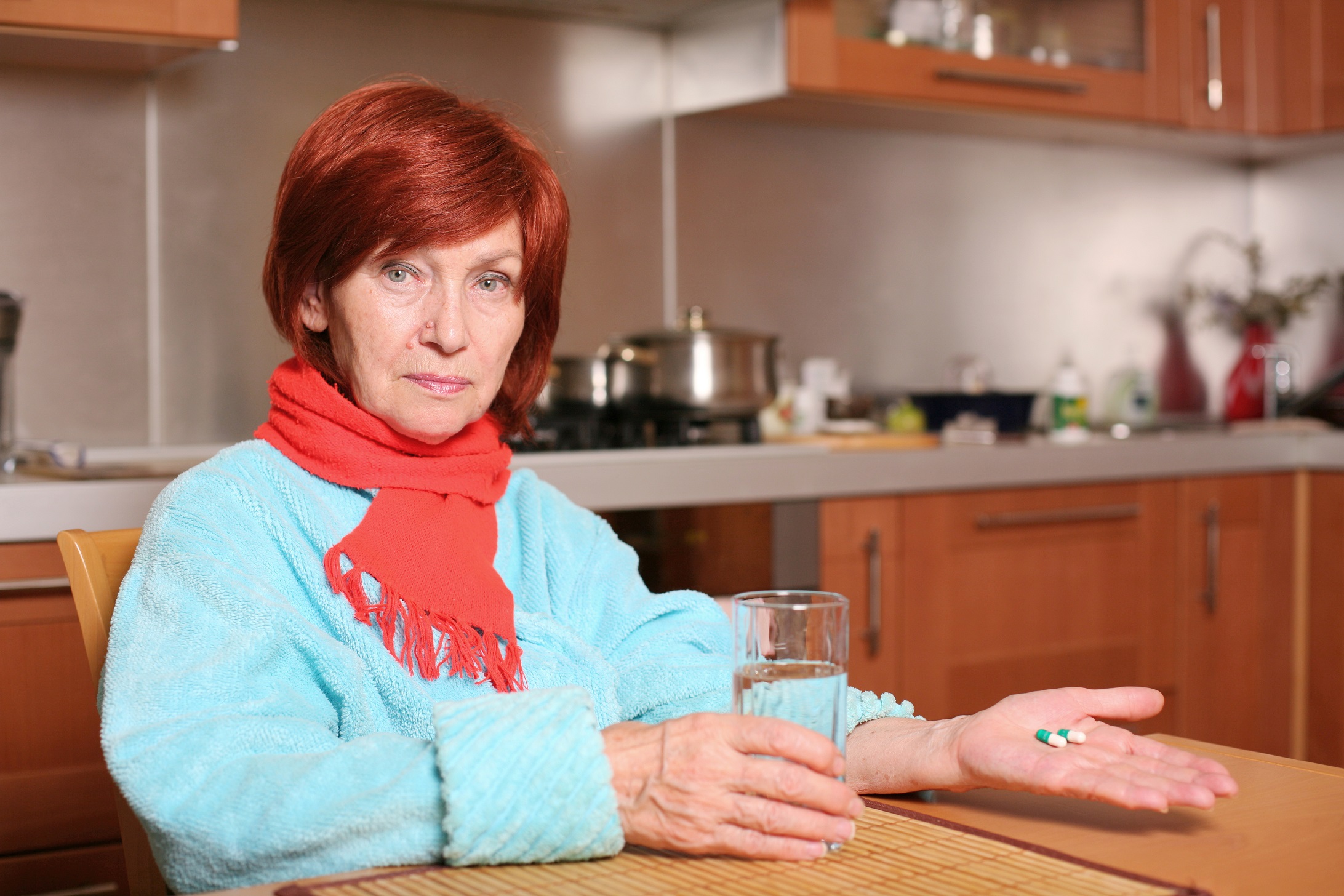 Senior woman holds pills and glass of water