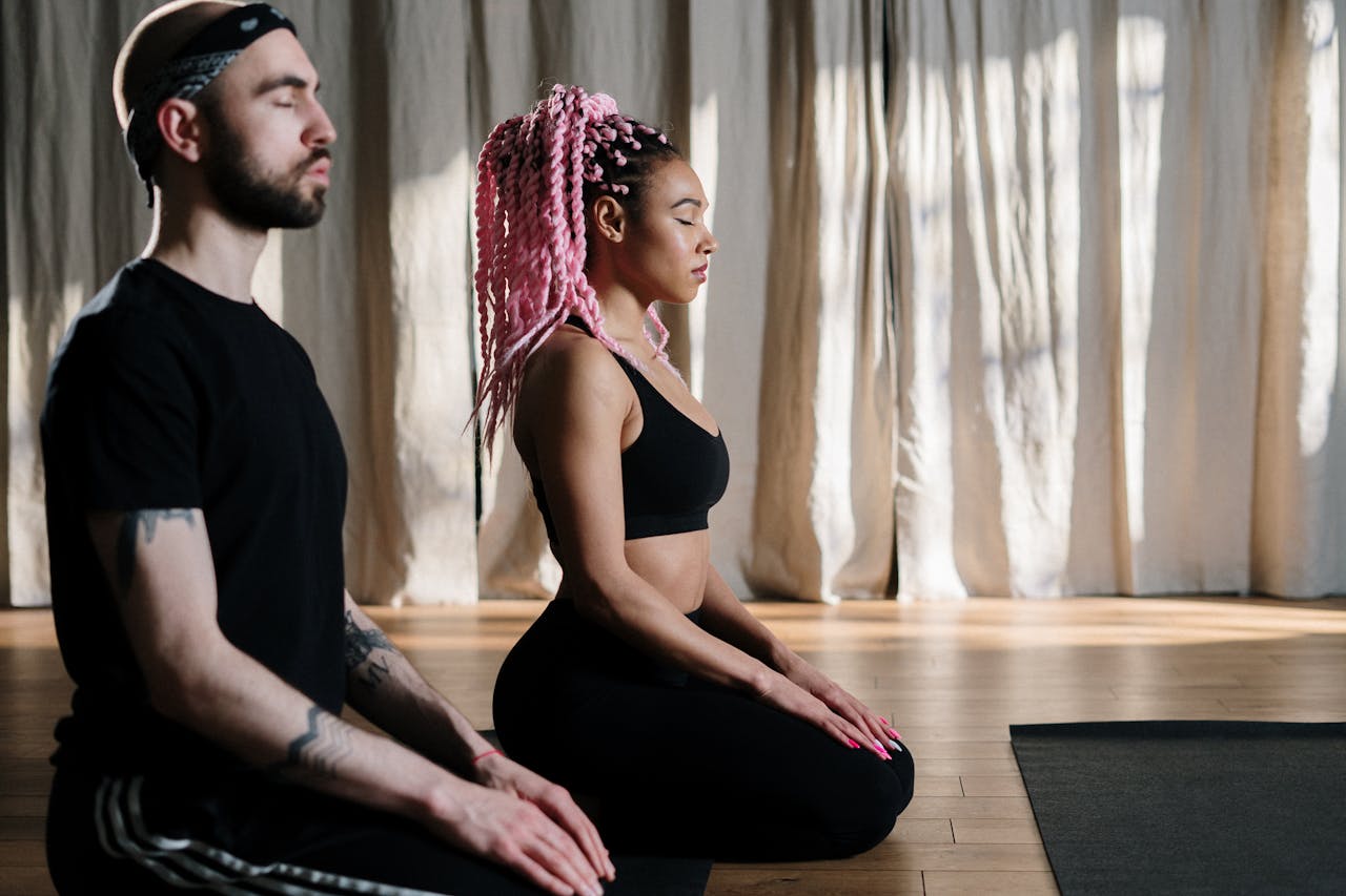 Woman in Black Tank Top is Sitting Beside Man in Black Shirt doing meditation.