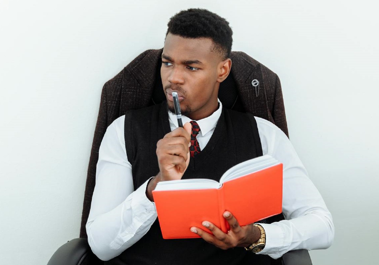 Man in Black Suit Holding a Notebook and Pen