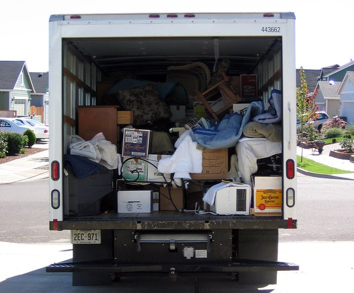 Close up Photo of a truck filled with home items parked in front of a house