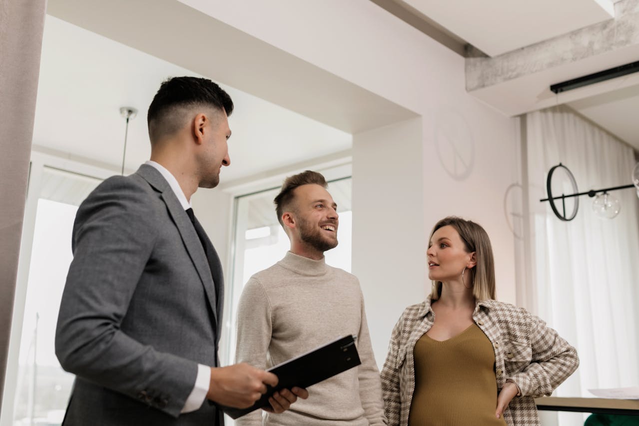 Man dressed in gray suit Talking to male and female Clients inside a house