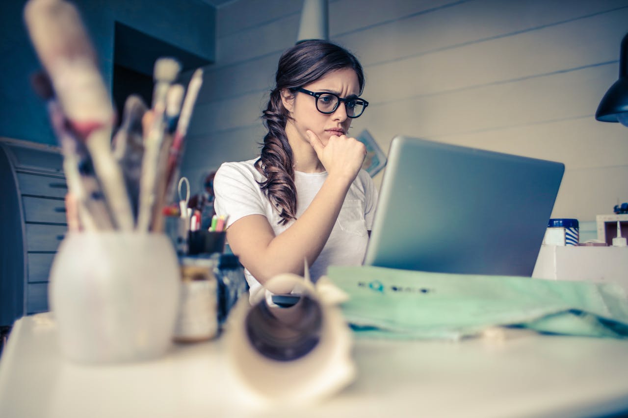 Portrait Photo of a Woman Thinking and looking in laptop on a desk