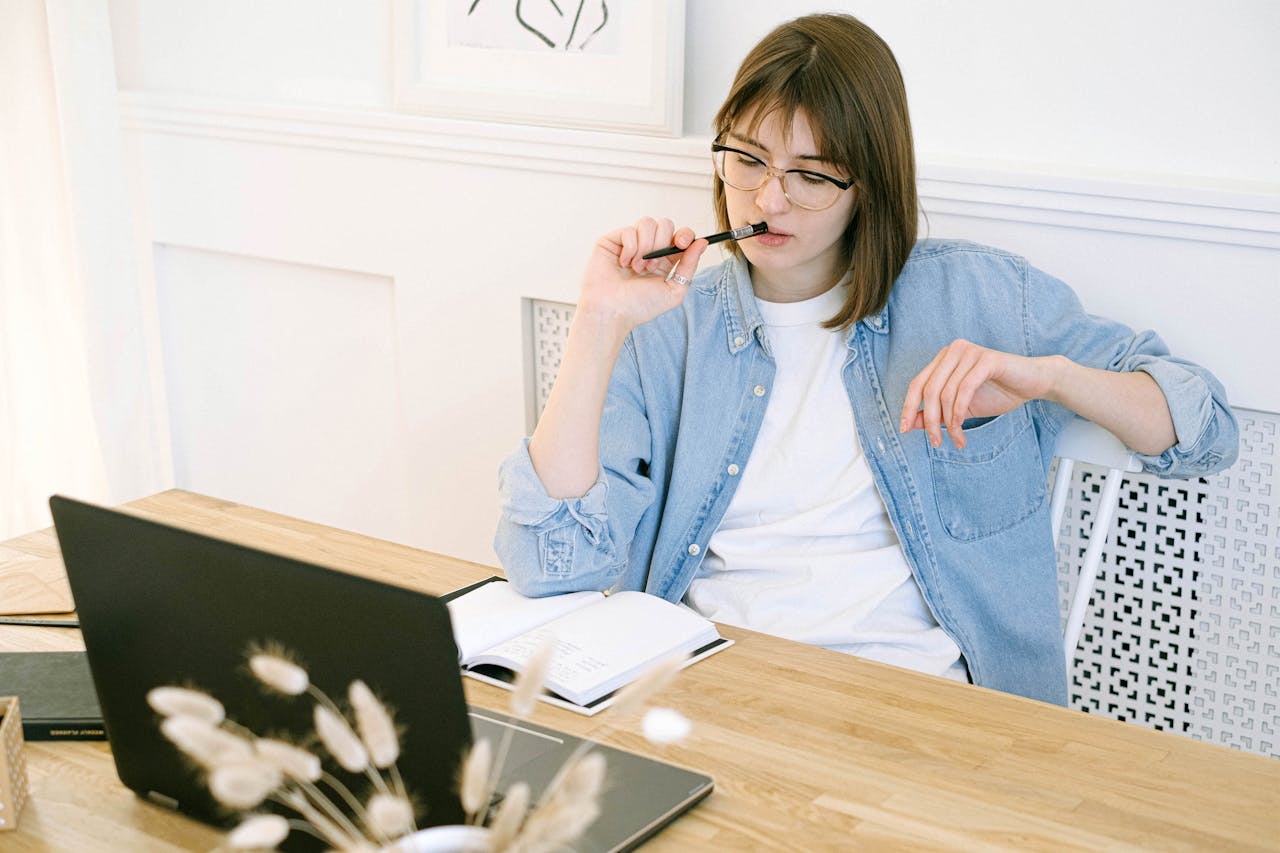 Portrait Painting of a Woman in a blue shirt Working in Home Office sitting on a wooden desk in front of a laptop