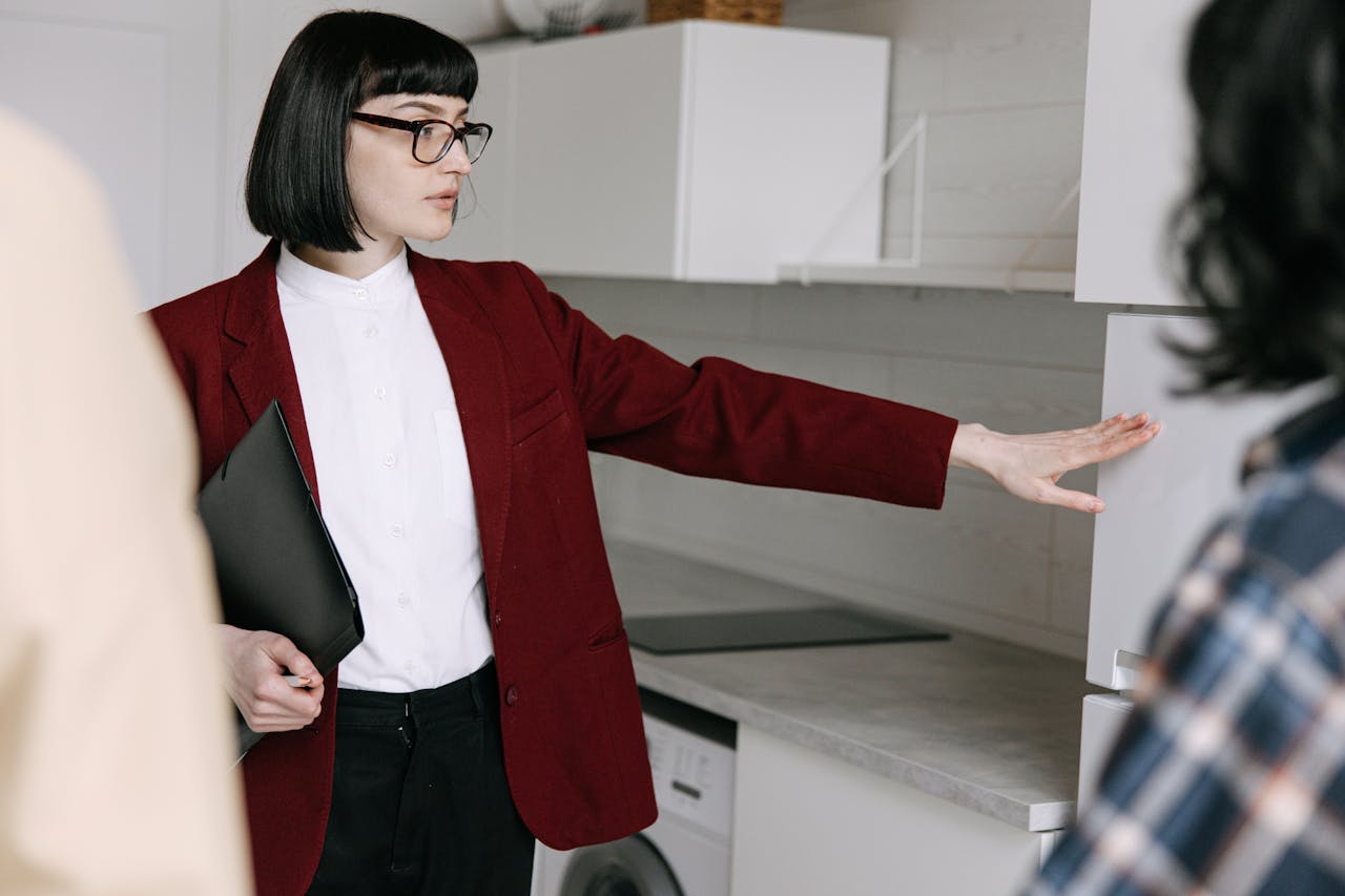 A Woman Showing the Kitchen Area of the House to clients