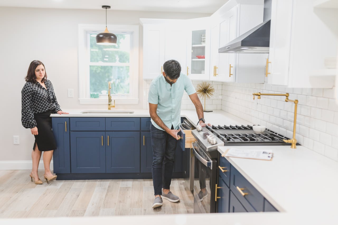A Man Inspecting the Kitchen Drawer and a woman standing next to the kitchen item
