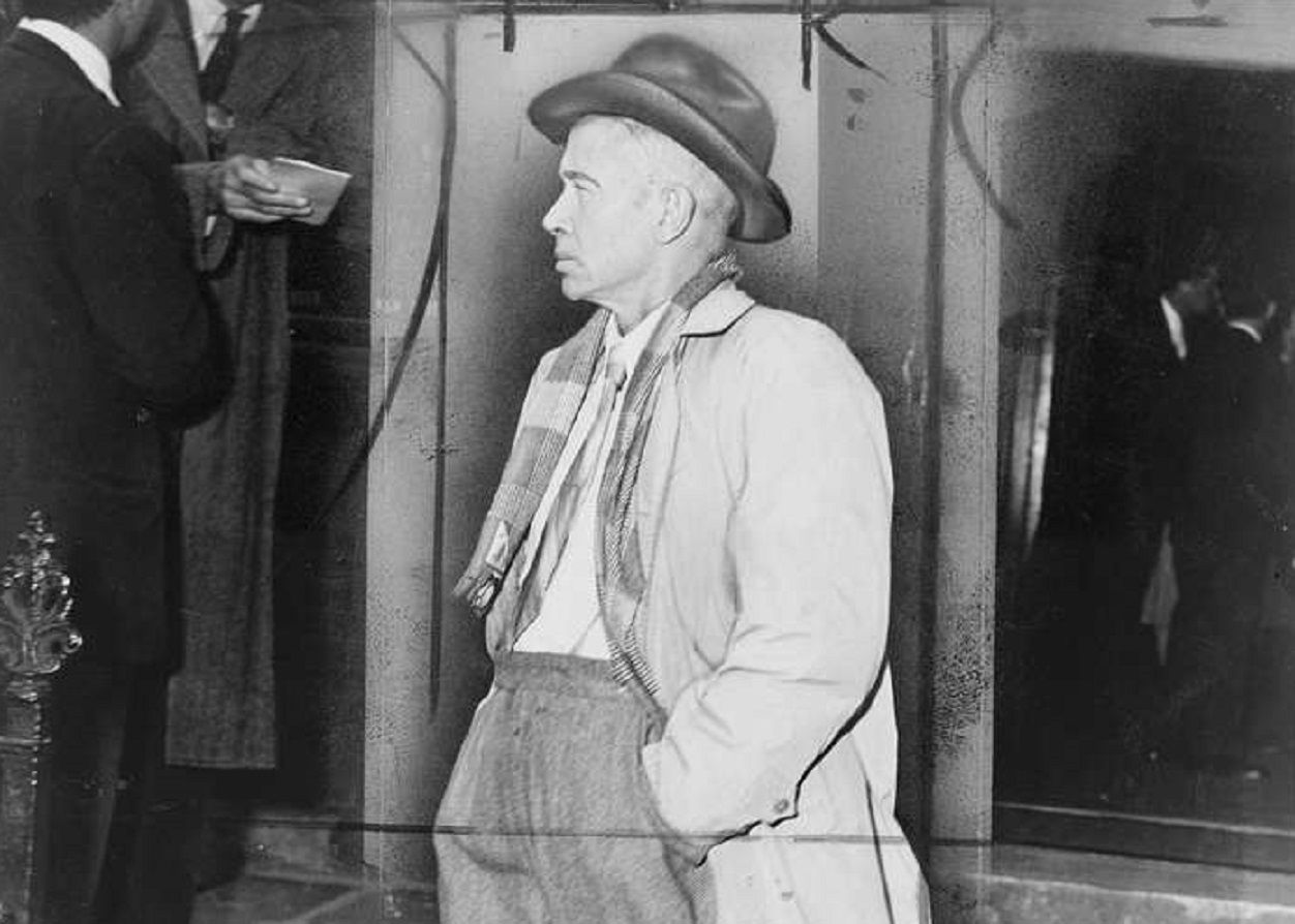 E.E. Cummings, facing left, wearing hat and coat.