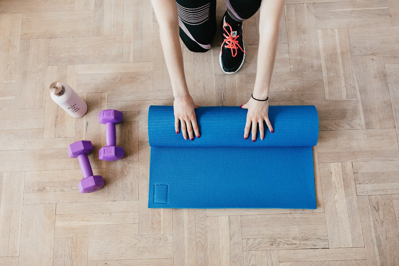 Woman unfolding sport mat on wooden floor