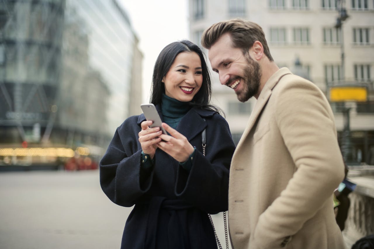 Man and woman standing in front of building and looking at phone