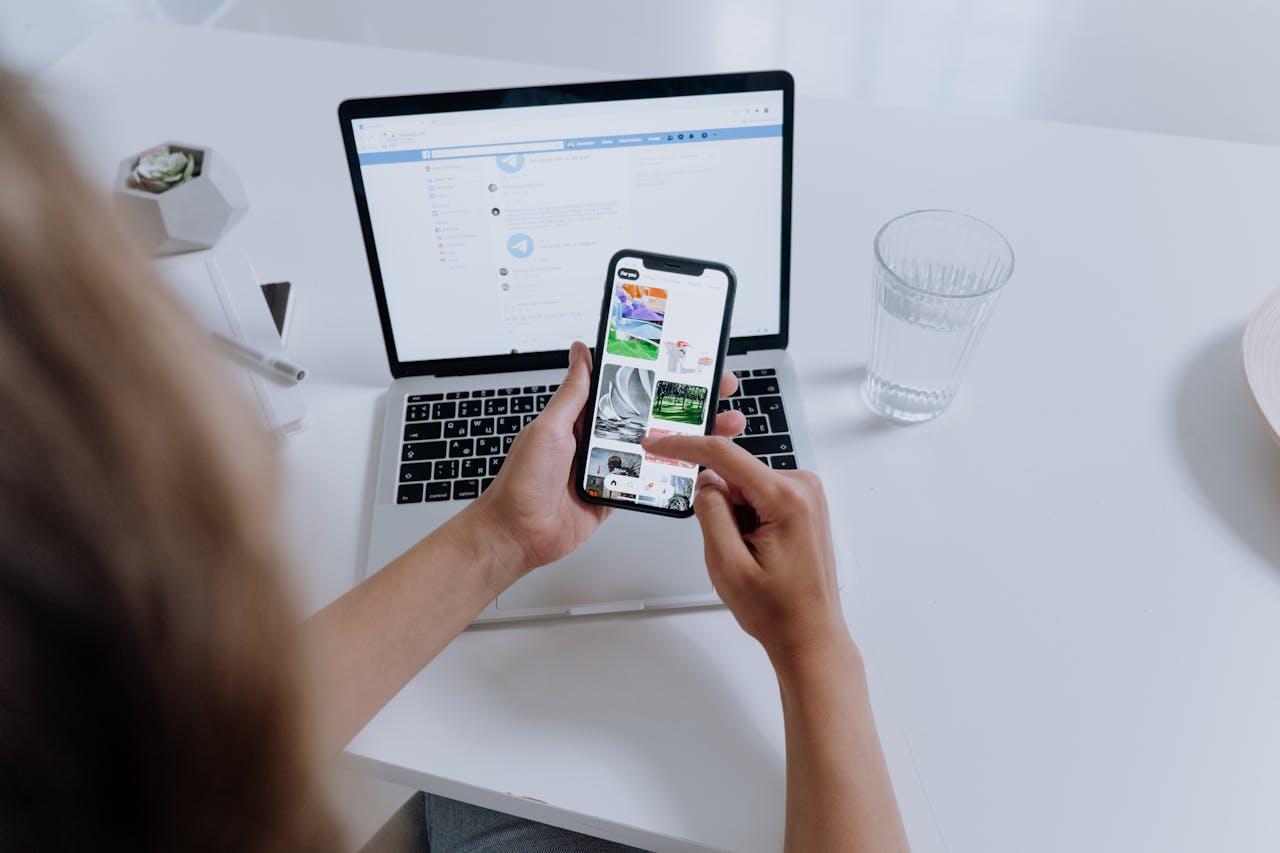 Person Using a Smartphone and Laptop on a desk