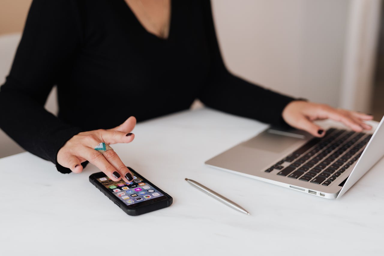woman using smartphone and laptop during work in office