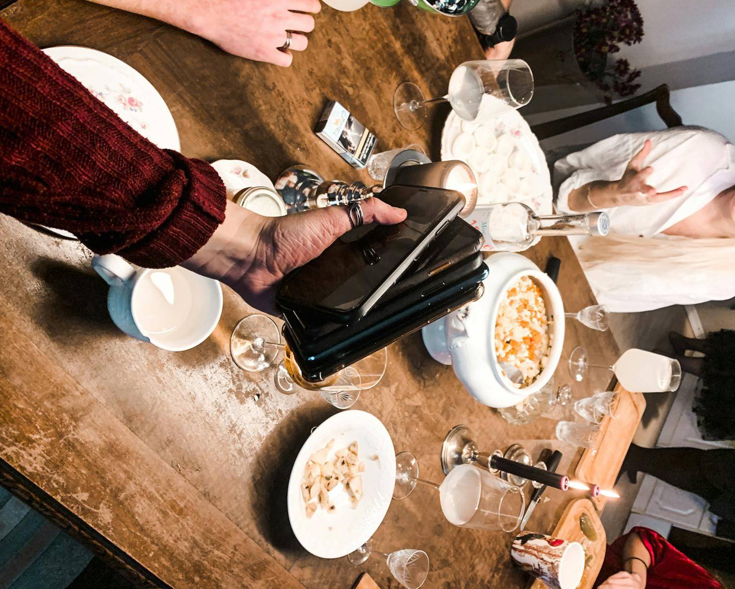 Man collecting smartphones from friends during dinner