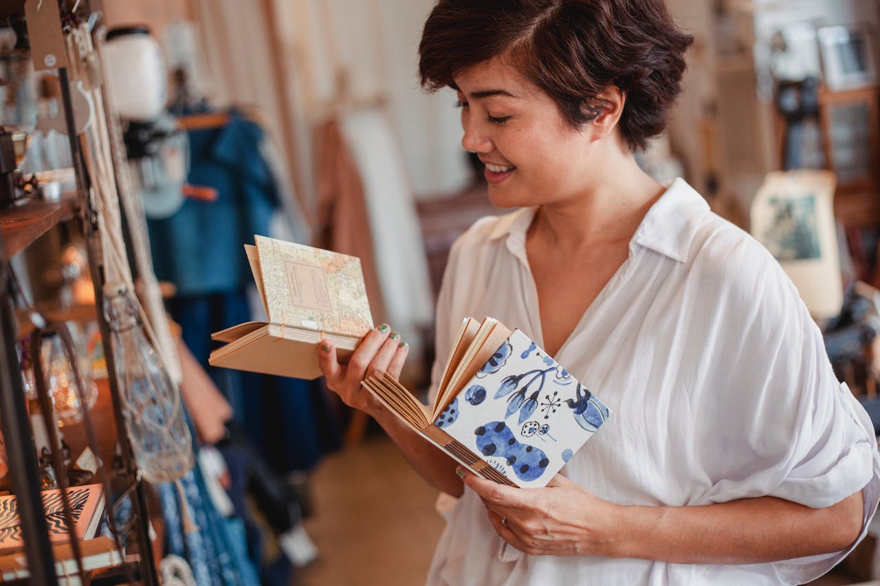Smiling young ethnic female selecting notebooks in souvenir store