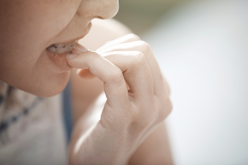 Close-up view on the woman biting nails