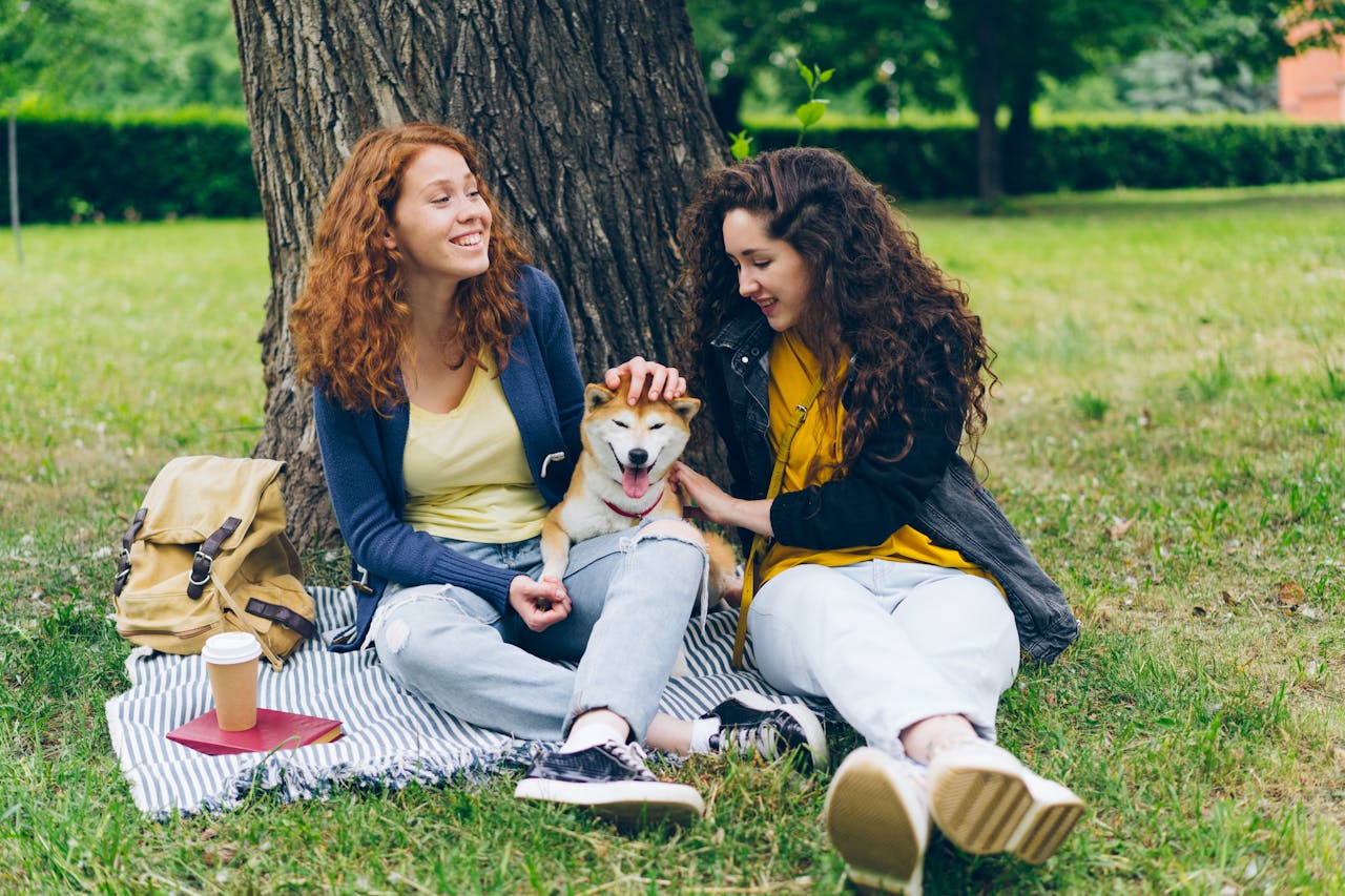 Two women and a dog sitting under the tree