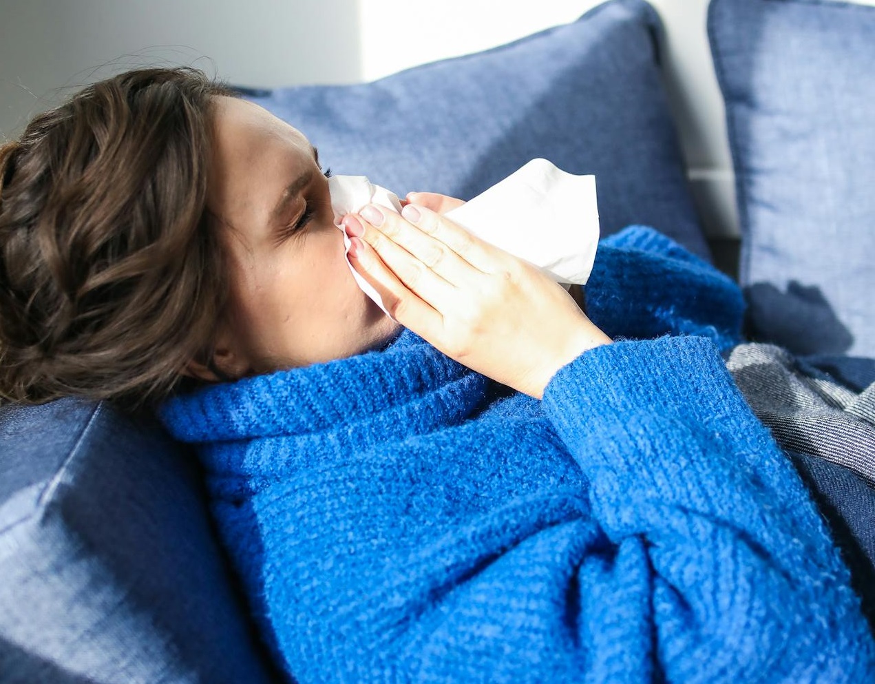 Sick woman in Blue Sweater Lying on Bed.