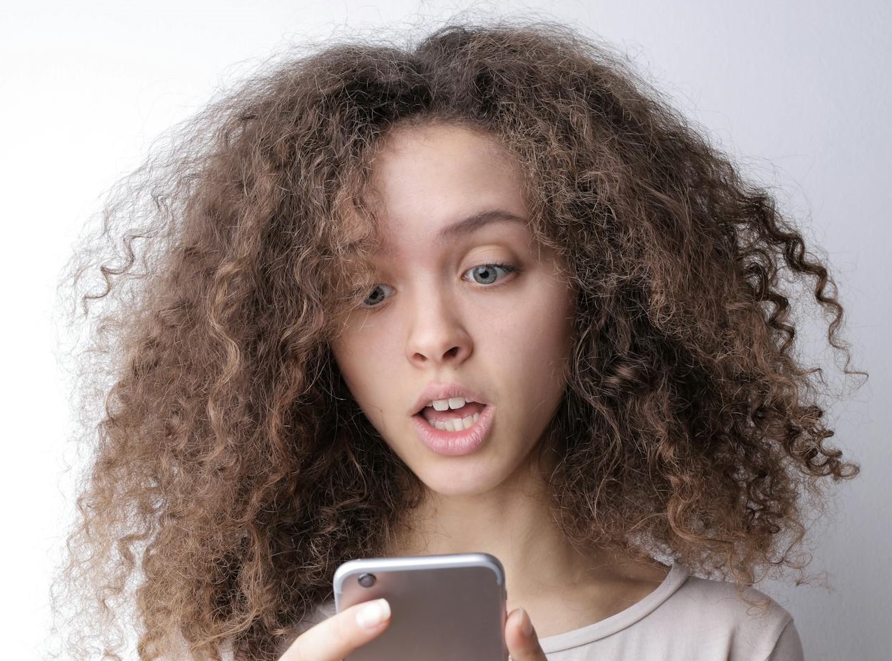 Surprised young woman browsing mobile phone