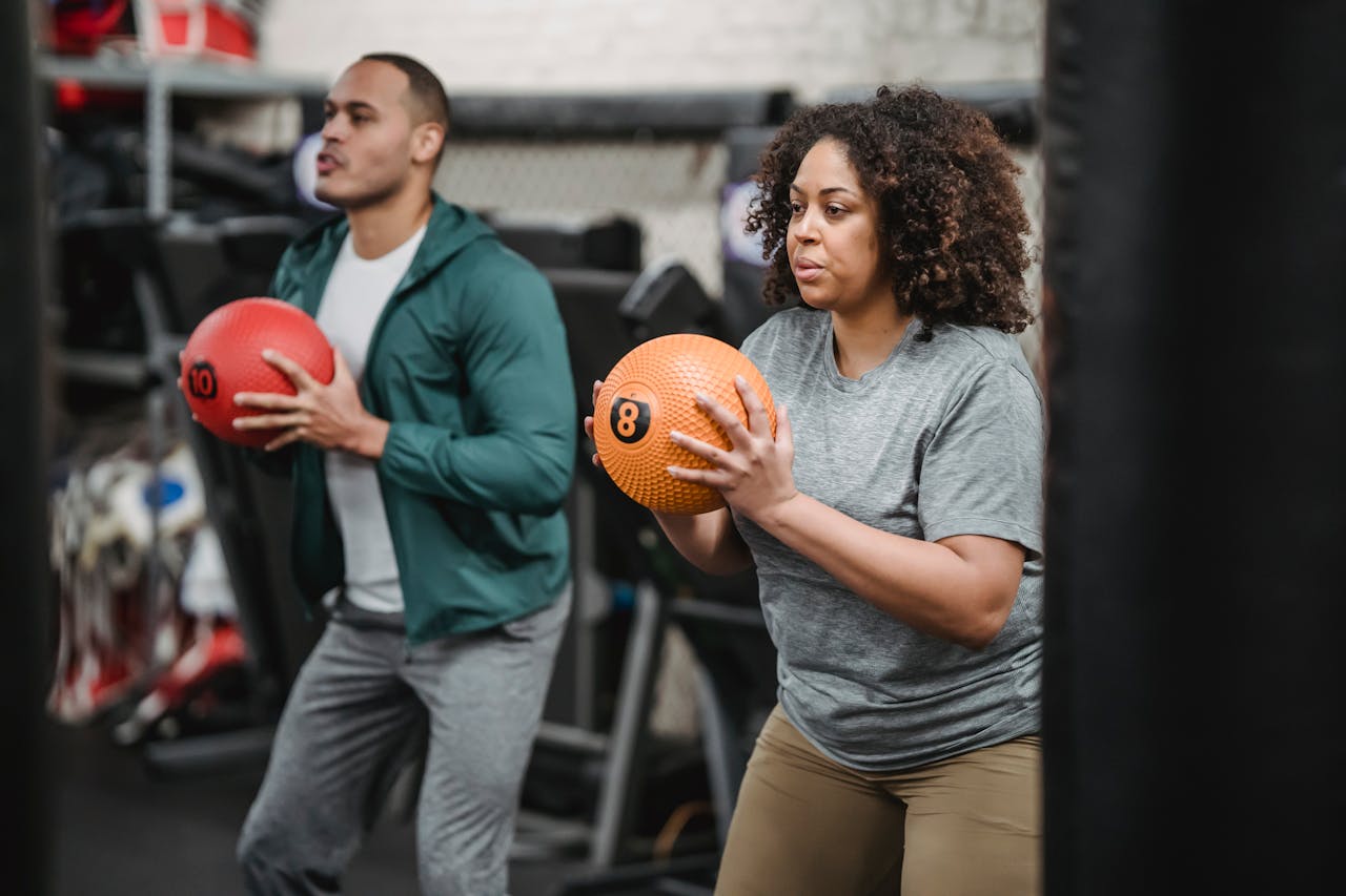 Trainer and athlete exercising with medicine balls