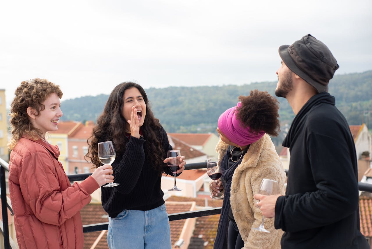 Friends Laughing While Holding Wine Glasses