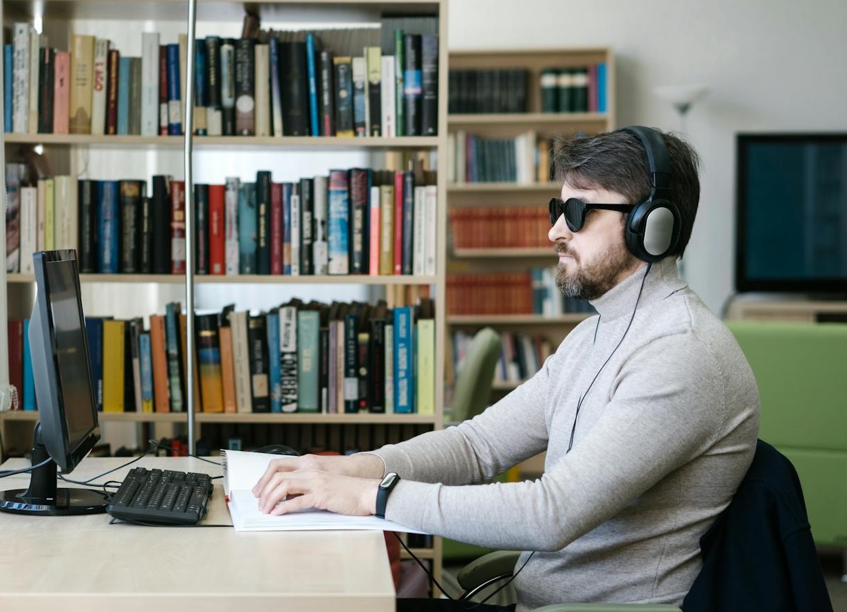 Blind Man in Gray Sweater listening on headphones.