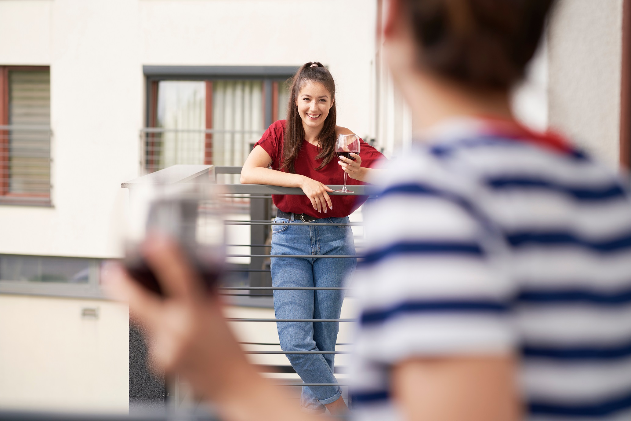Women chatting while standing on their balconies