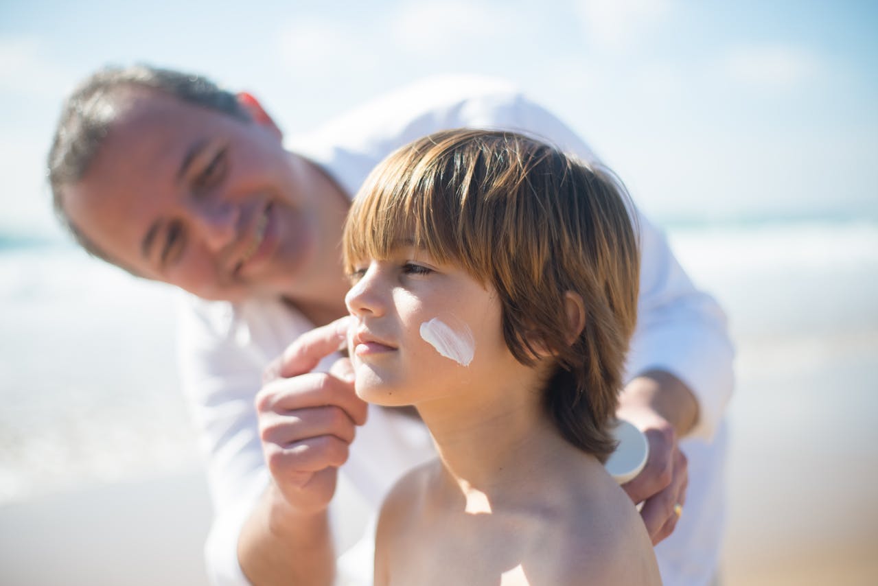 A Man Applying a Sunscreen on His Son's Face