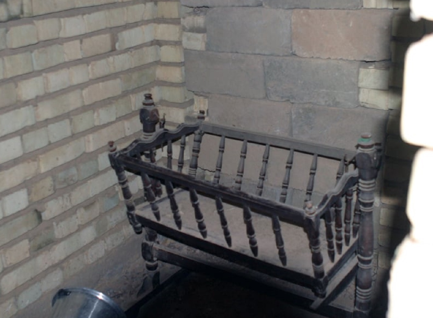 A baby crib collects dust in a little room.