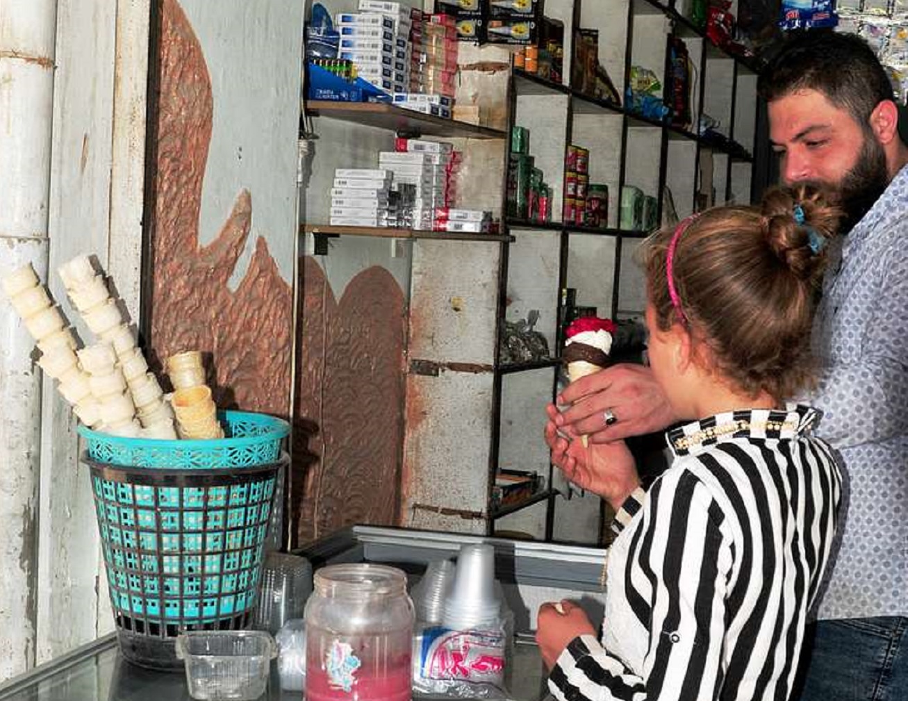A man serves ice cream to children at a market.