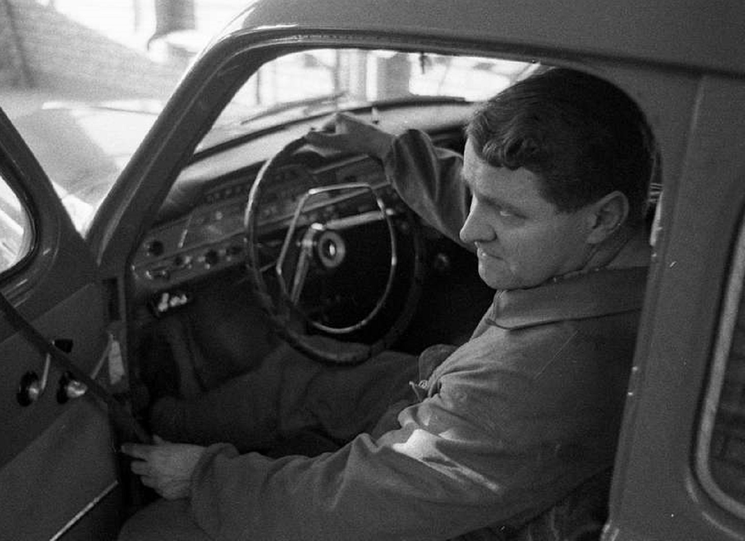 Man seating in car with open door - 1965