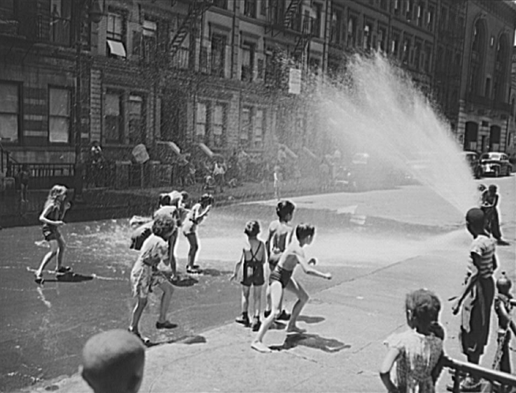 Children escape the heat by using fire hydrant as a shower bath.