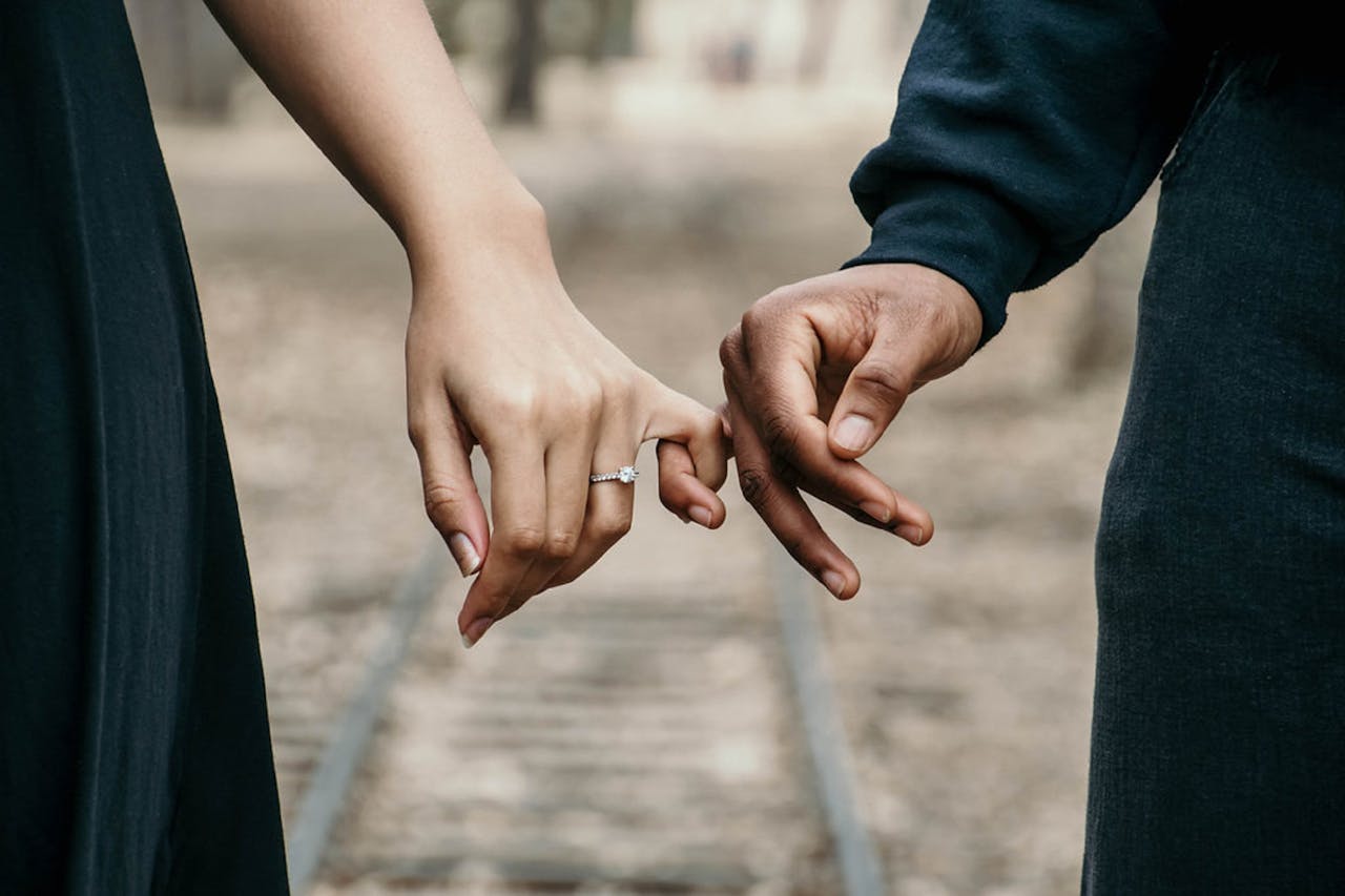 image of a man and woman holding hands with pinky fingers