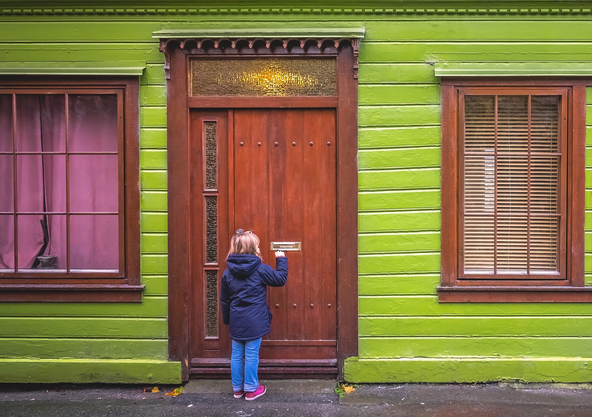 Little girl is knocking at the wooden door.