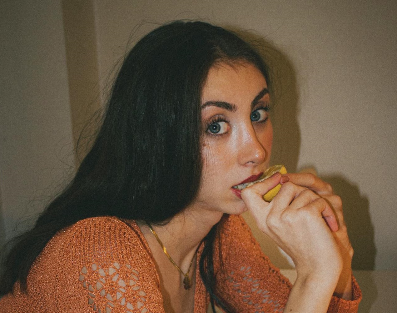 Woman Eating Lemon and looking at camera.