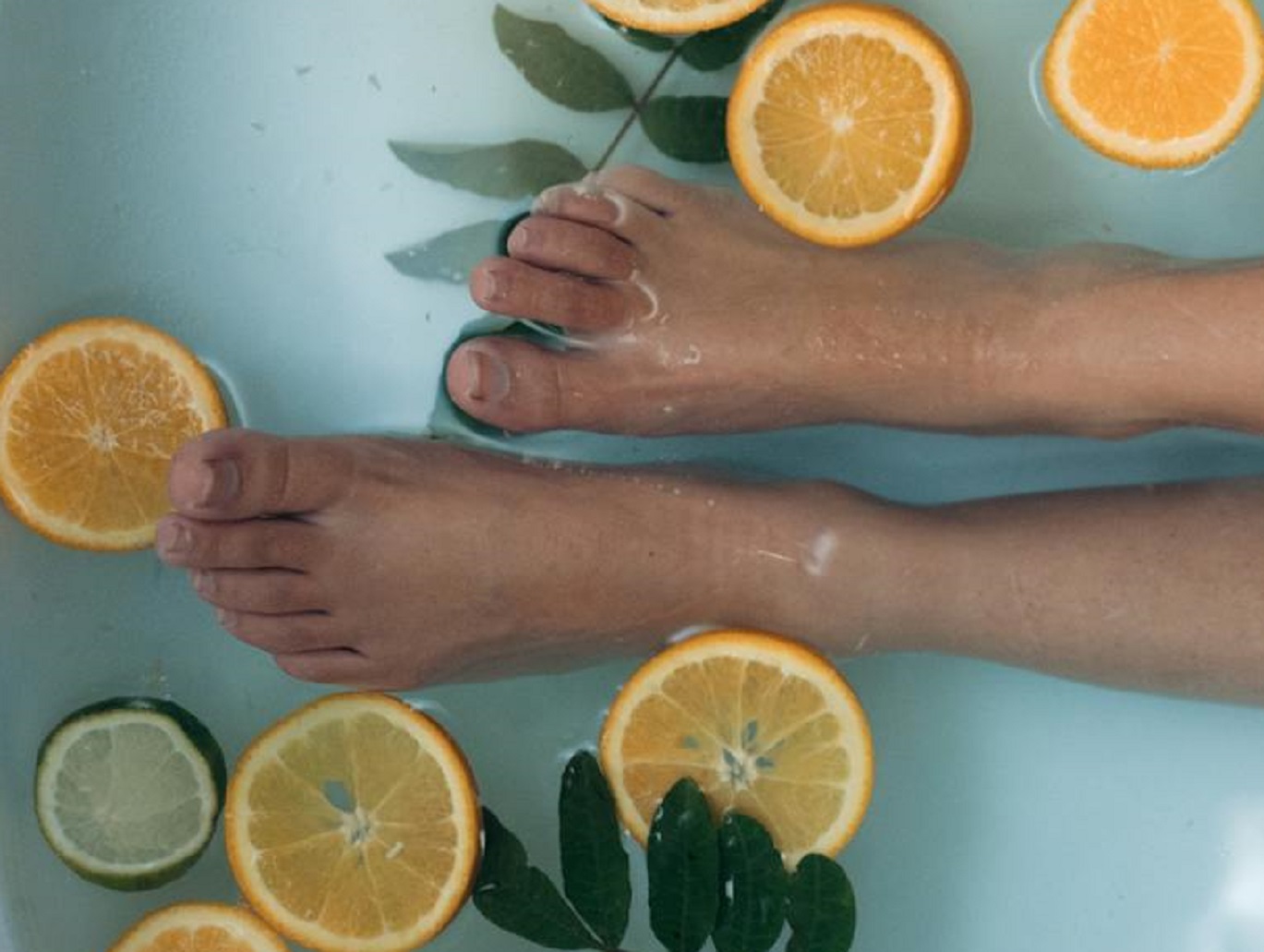 Woman feet in bath tub with sliced lemons.