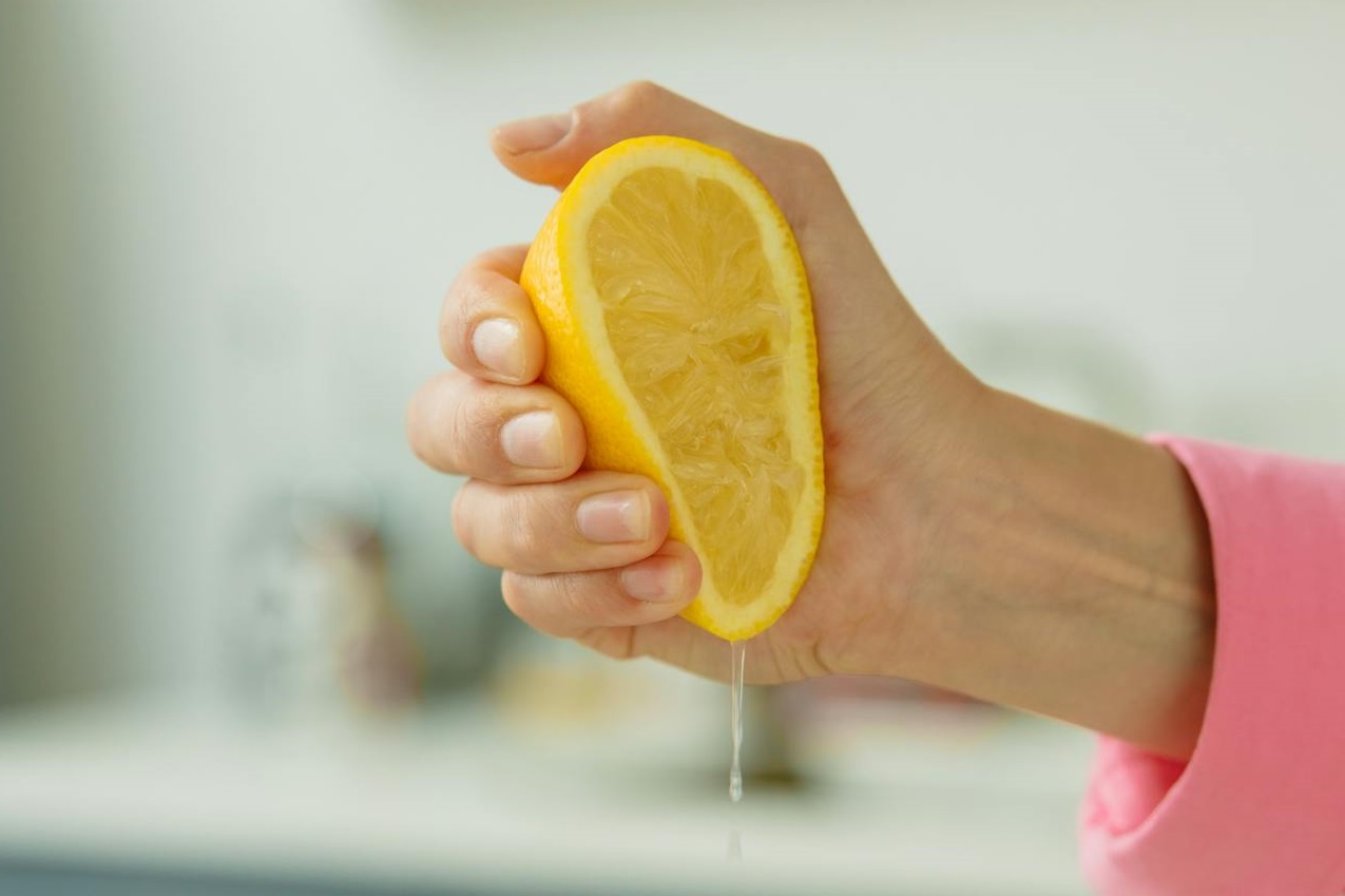 Person Squeezing Sliced Lemon